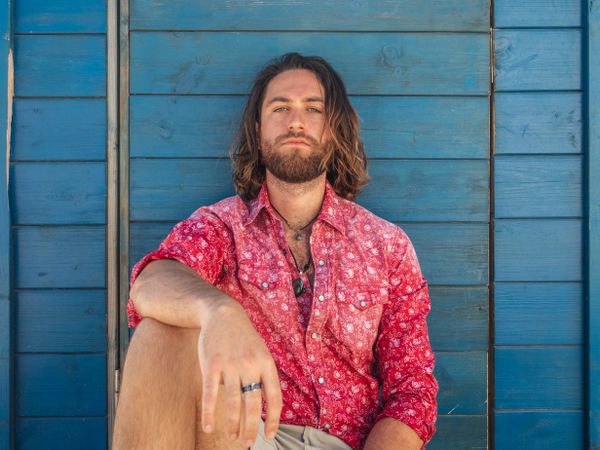 Cheerful guy sitting near blue wall