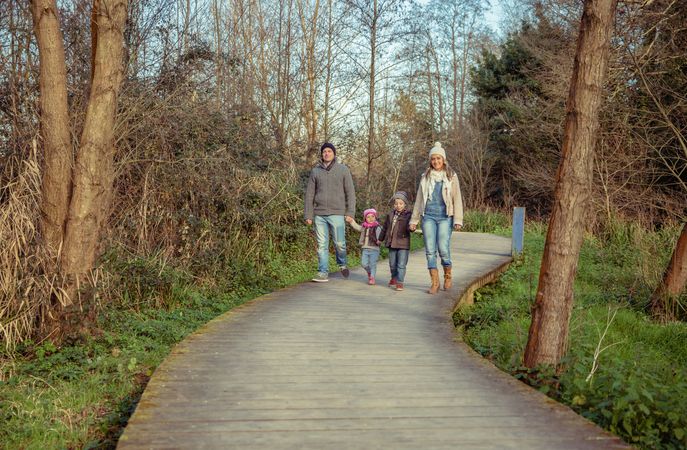 Young family walking together on forest trail