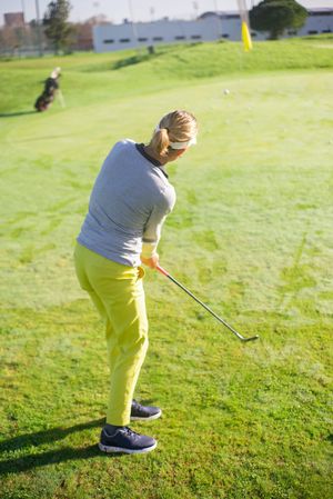Back view of blonde woman in yellow pants playing golf