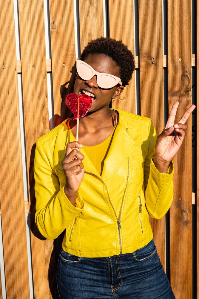 Cool female eating candy and showing v sign