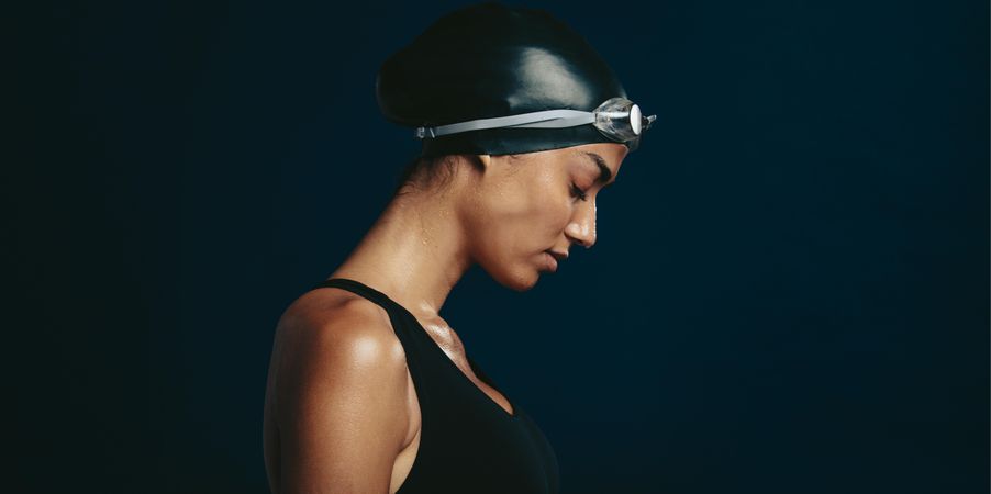 Side view of a professional female swimmer with goggles and a hat