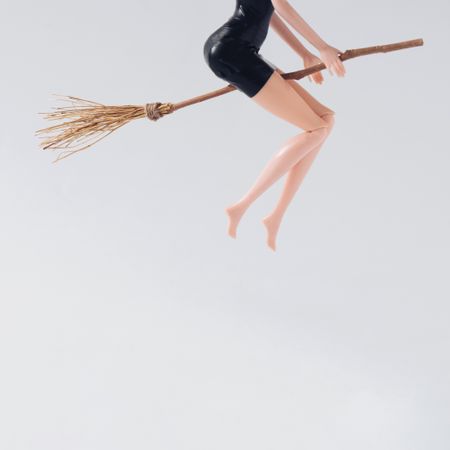 Doll in dark dress on broomstick