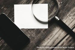 Piece of paper, cell phone magnifying glass on wooden table 4ZdZ90