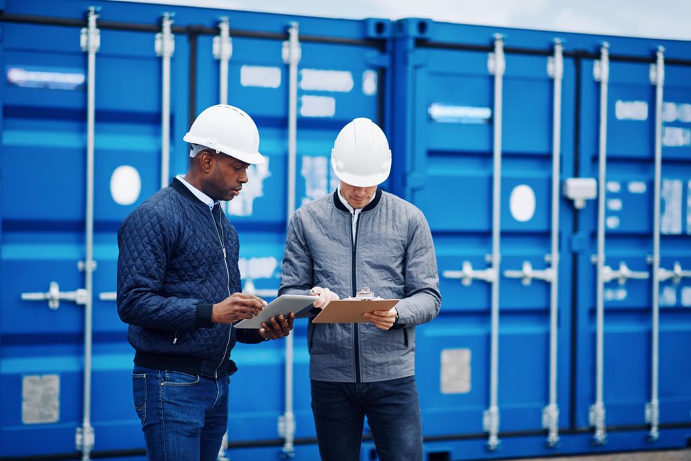 Two men in hard hats discussing plans on a building site