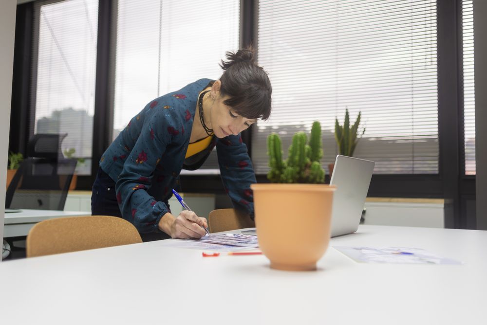 female working with documents while standing at desk in modern office