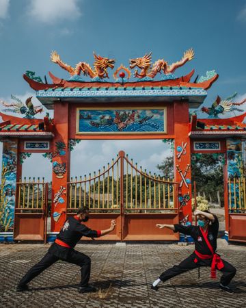 Two men sparring in wushu fighting beside a Chinese temple outdoor