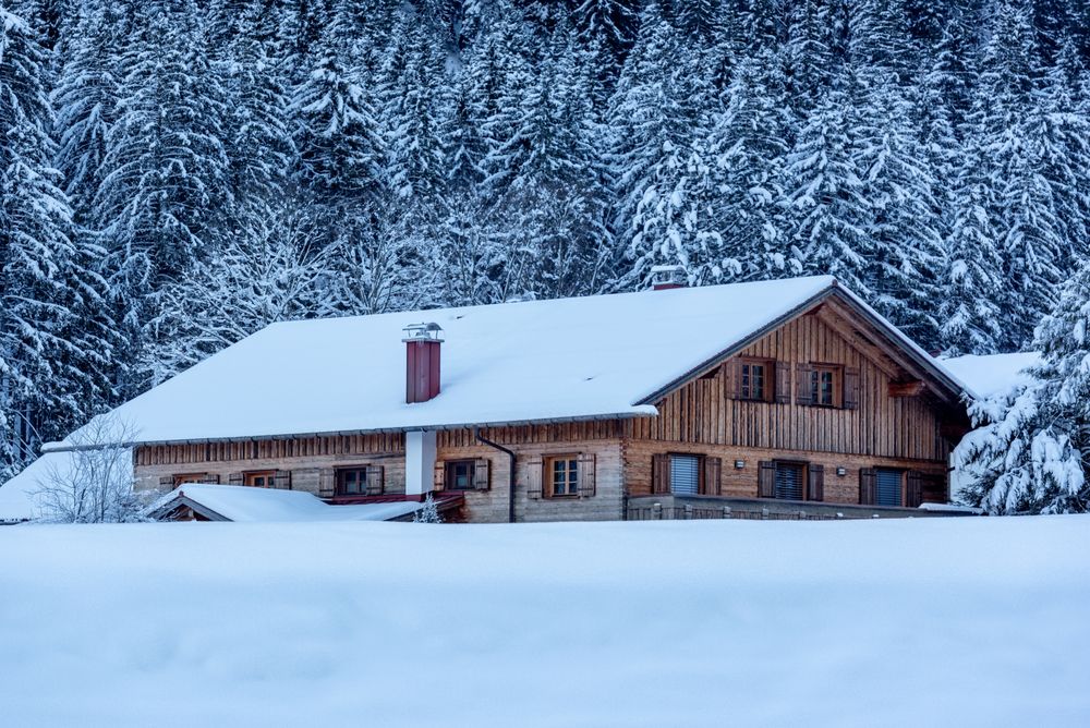 Log cabin covered in deep snow in December, in the Bavarian Alps, Germany