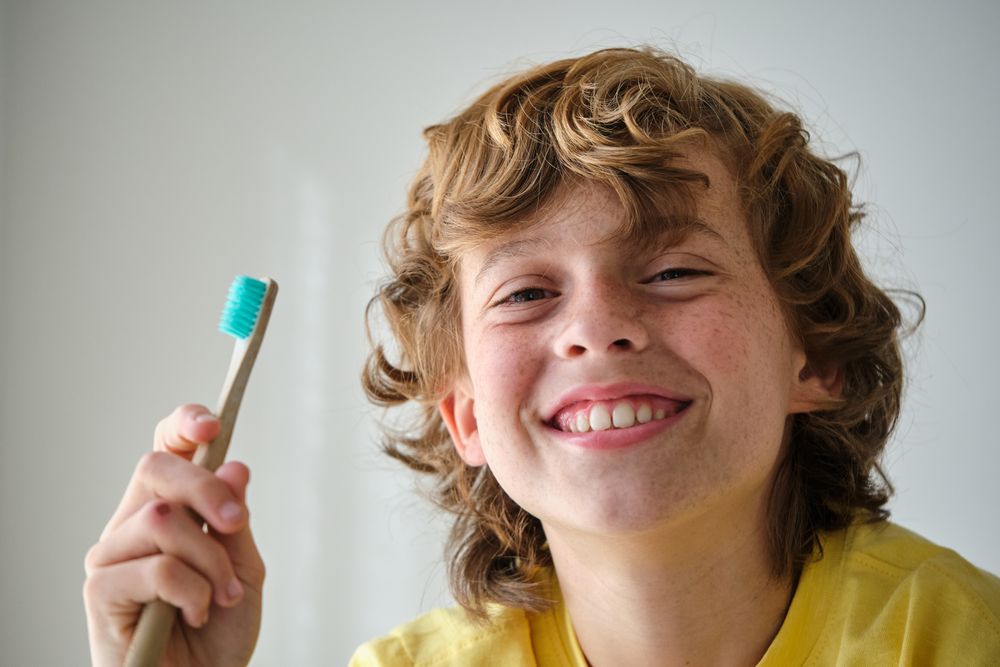 Smiling child with toothbrush on light background
