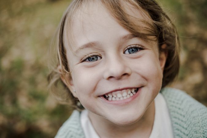 Smiling girl between meadow with dry leaves