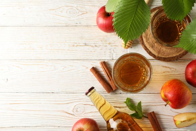 Composition with cider, cinnamon and apples on wooden background