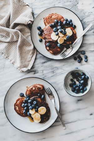 Pancakes with banana, blueberries and honey on marble table