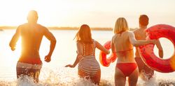 Multi-ethnic group of friends running into the lake