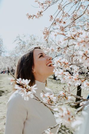 Young happy woman between trees in garden