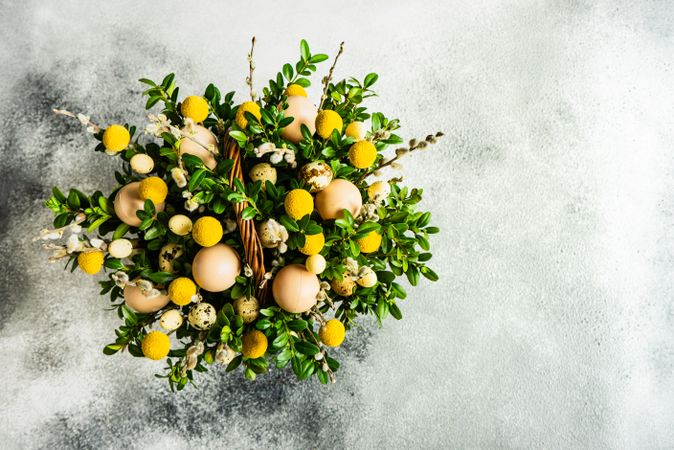 Top view of Easter card concept with fresh basket of greenery with decorative eggs