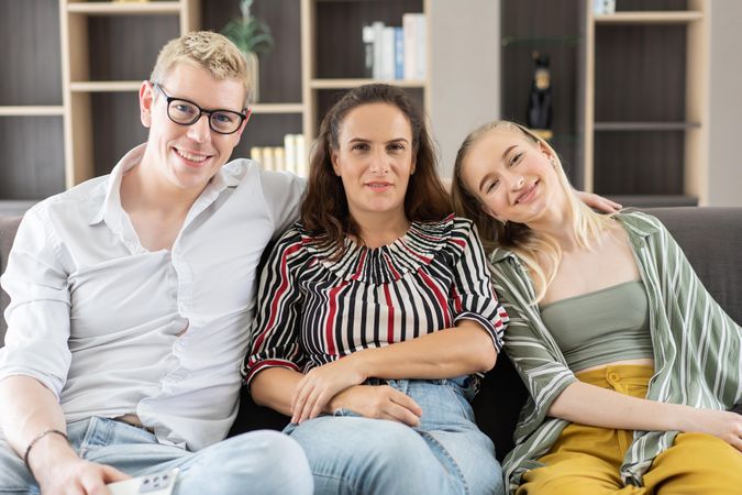 Portrait of happy family sitting on couch in the living room smiling and looking at camera
