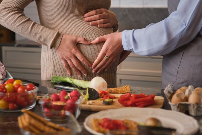 Crop woman touching belly of pregnant friend