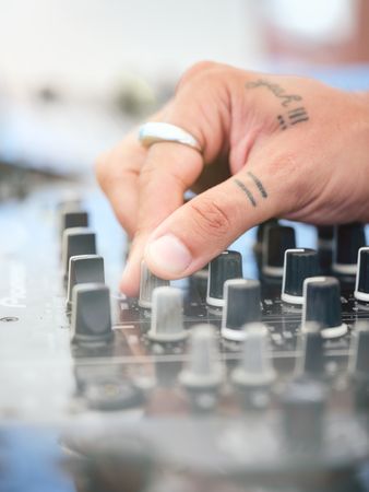 Unrecognizable DJ adjusting sound of disco music