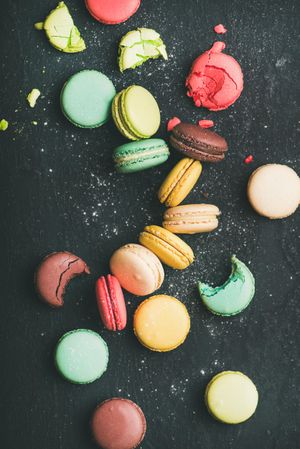 Assortment of multi-colored macaron pastries against a dark background, vertical composition