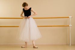 Ballet dancer adjusts her tutu in dance studio