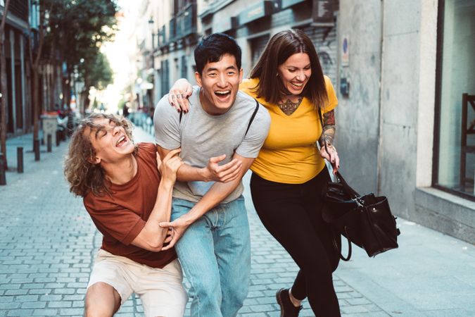 Funny multiracial friends having fun along city street