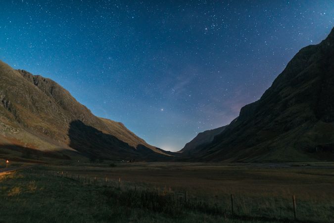 Field near mountain under sky full of stars