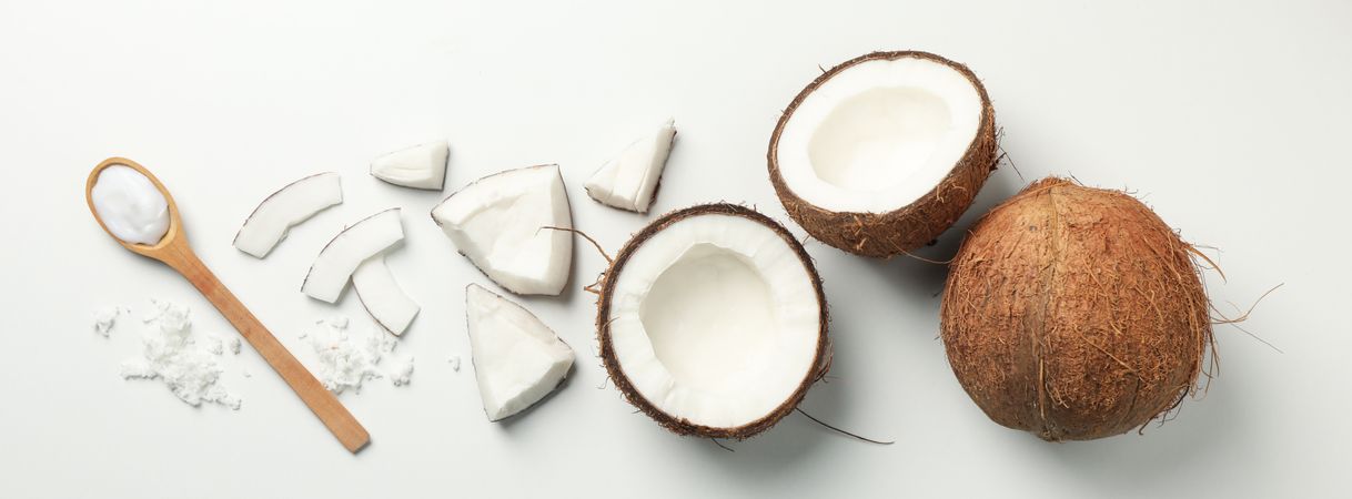 Flat lay with coconut and spoon on plain background, top view