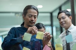 Male brainstorming with sticky notes in office with colleagues
