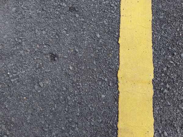 Asphalt road texture with yellow dividing line.