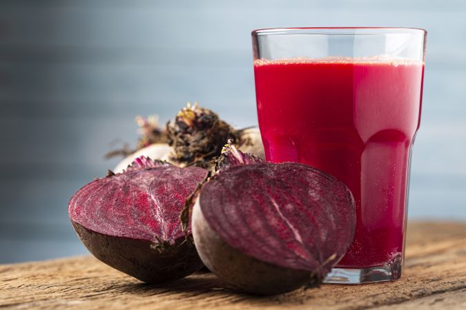 Red beet juice in a glass cup on the wooden table.