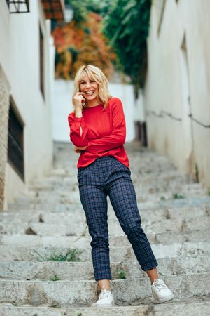 Happy blonde woman with red shirt standing on steps outdoors