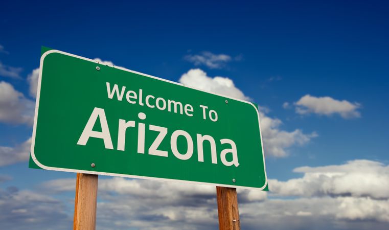 Welcome To Arizona Green Road Sign Over Blue Sky with Some Clouds.