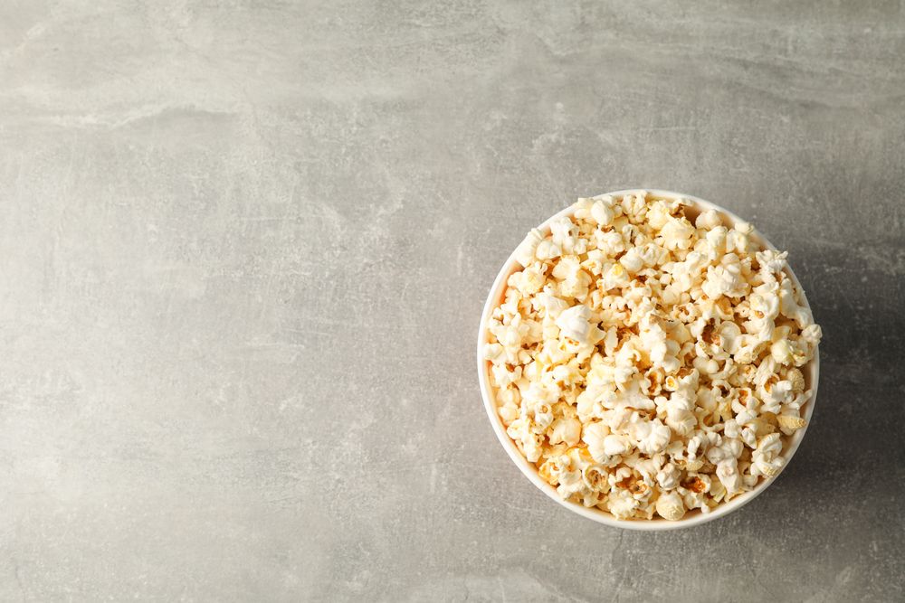 Bucket with popcorn on grey background, space for text