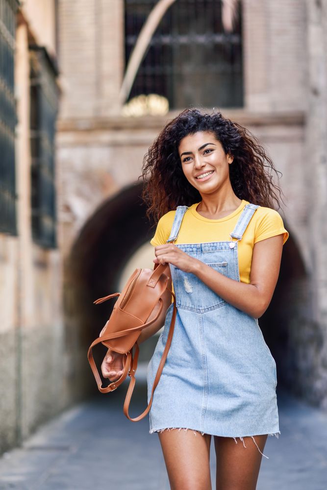 Content Arab woman walking through quiet street with arch