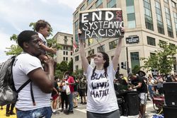 Woman holding anti-racism sign next to father with son on shoulders, Washington, D.C.