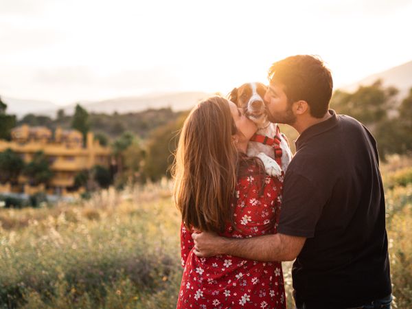 Happy couple with friendly cute dog outdoors