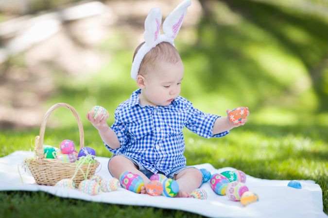 Boy Outside Wearing Rabbit Ears Playing with Easter Eggs