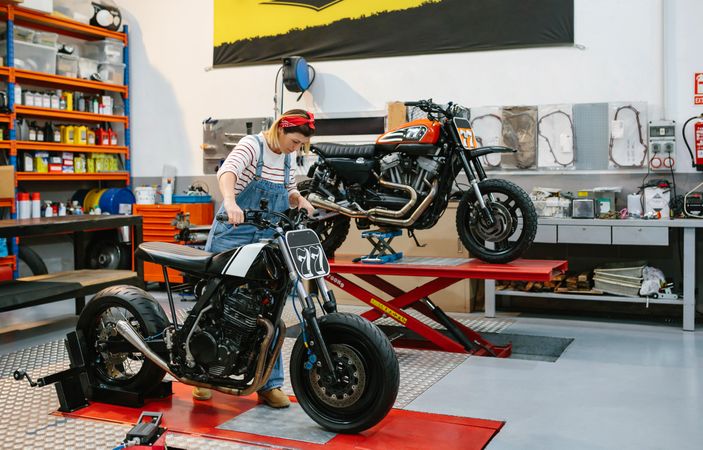 Mechanic woman placing custom motorcycle over platform