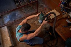 Man grinding wooden plank at joinery
