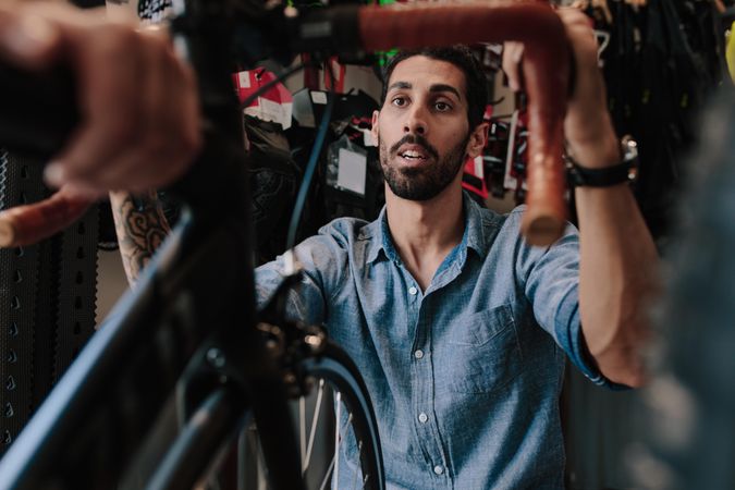 Man with beard inspecting a bicycle handle for alignment
