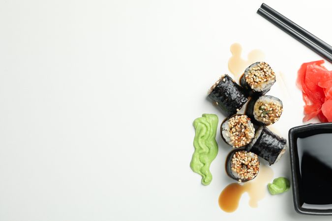 Delicious sushi rolls, sauces and chopsticks on plain background, space for text