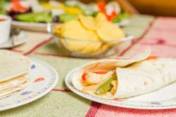 Traditional mexican food with a plate of chicken fajita, tortillas, fresh salad and a bowl of nachos