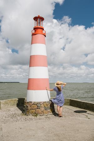 Woman on seashore beside lighthouse