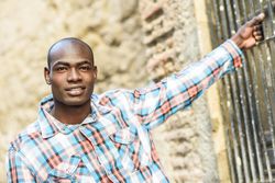 Happy male in plaid shirt with arm holding onto window bars