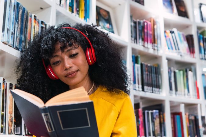 Content female student reading textbook in library