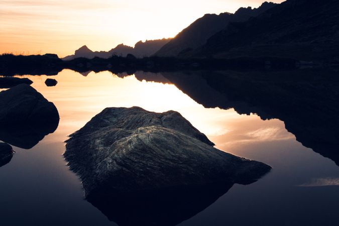 Calm lake in sunset light surrounded by mountains
