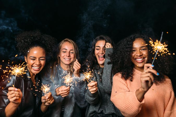 Multi-ethnic group of happy women at party with sparklers