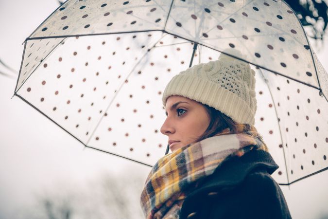 Side view of woman under an umbrella on rainy day