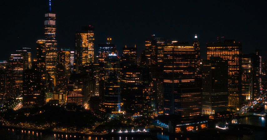 Wall Street Office Buildings Lit Up at Night: Scenic Aerial New York City View of Lower Manhattan Architecture. Panoramic Financial District Photo from a Helicopter. Evening Cityscape of NYC