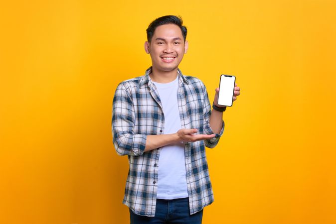 Asian male showing blank screen of smart phone in studio shoot