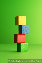 Colorful wooden blocks stacked over green background 4Ap6q5